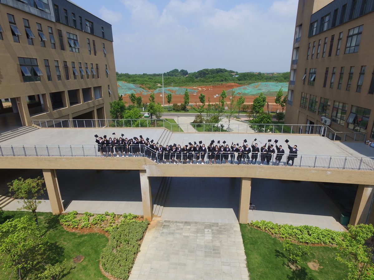 Aerial view of students in graduation gowns on a bridge between buildings.
