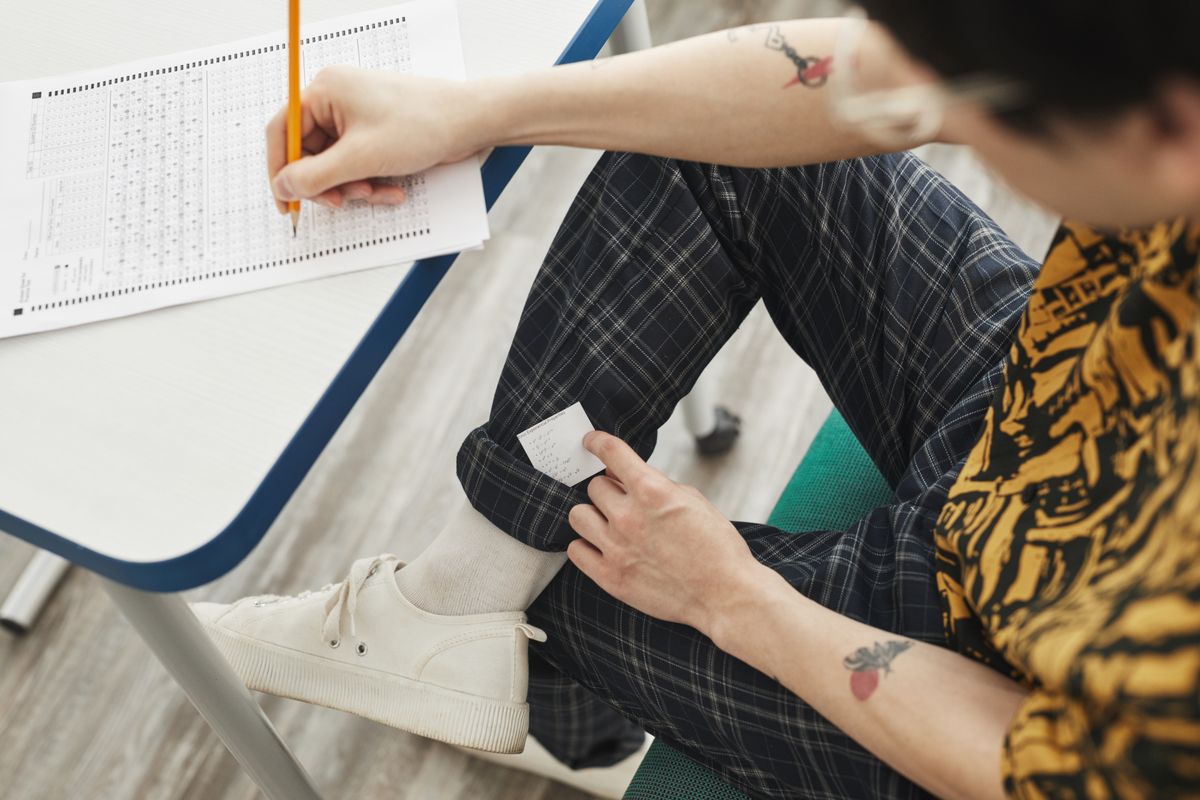 A student using hidden notes to cheat during an exam, showcasing academic dishonesty.