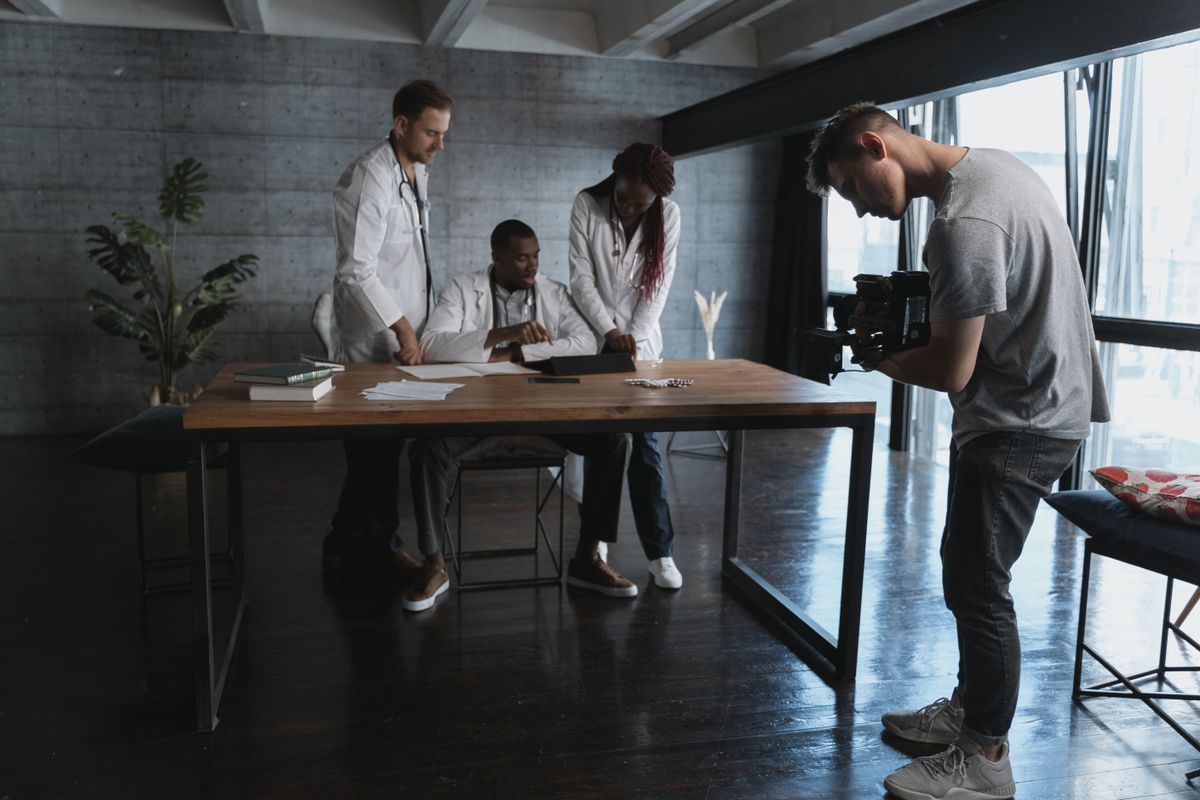 Doctors and filmmaker collaborating in an office setting, highlighting teamwork.