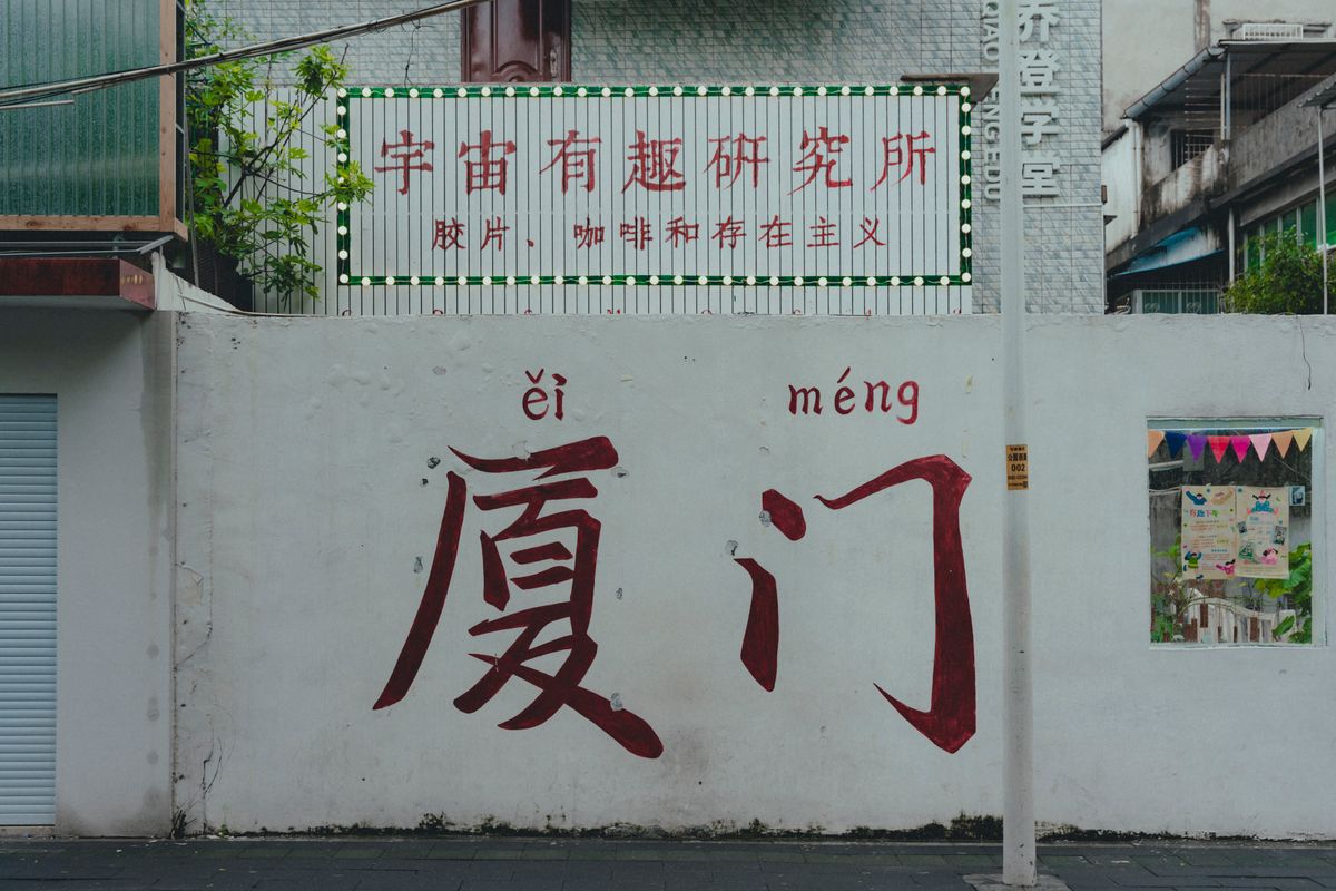 Urban scene featuring a wall with Chinese graffiti and colorful signage.