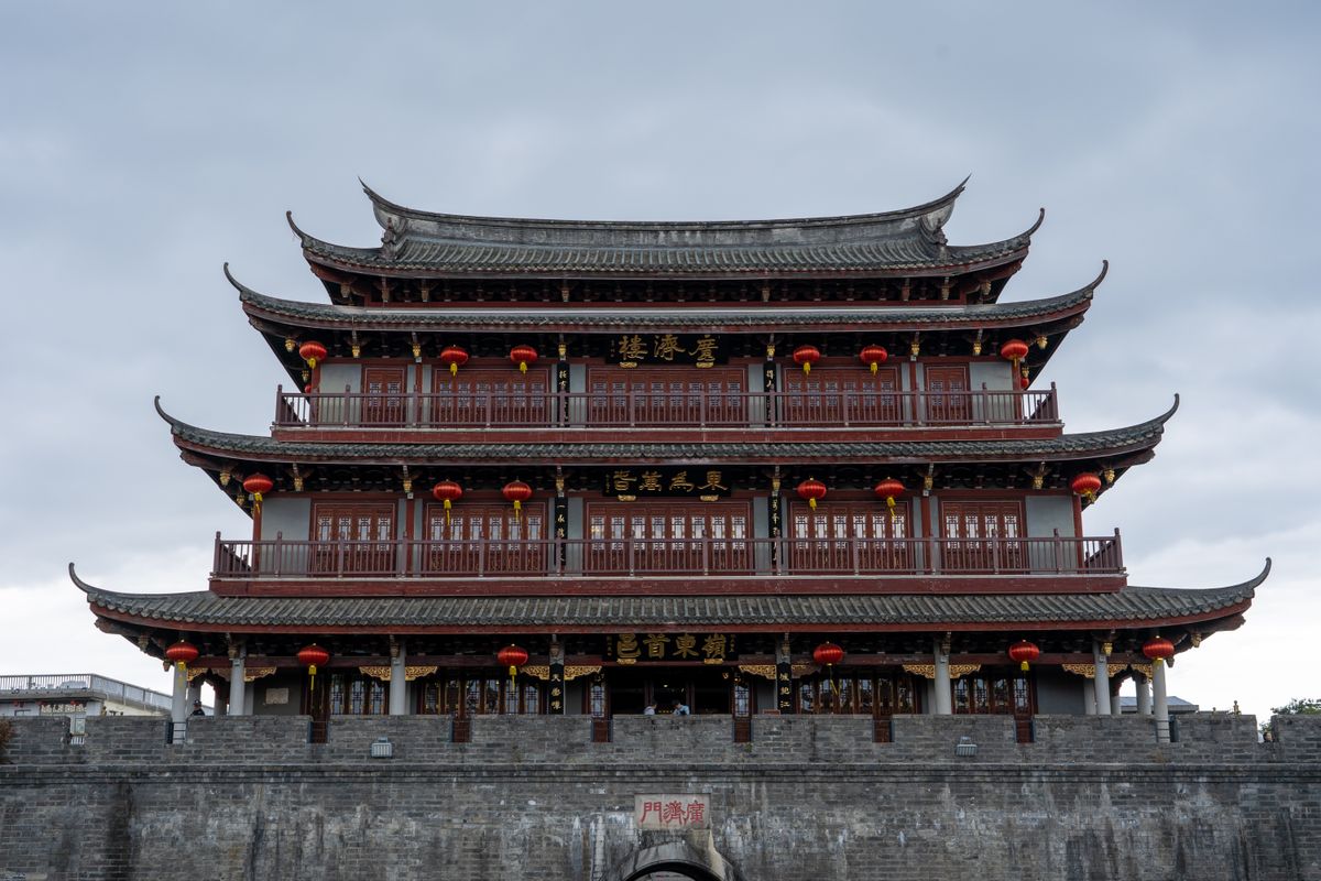 A classic Chinese pagoda adorned with red lanterns under a cloudy sky, showcasing traditional architecture.