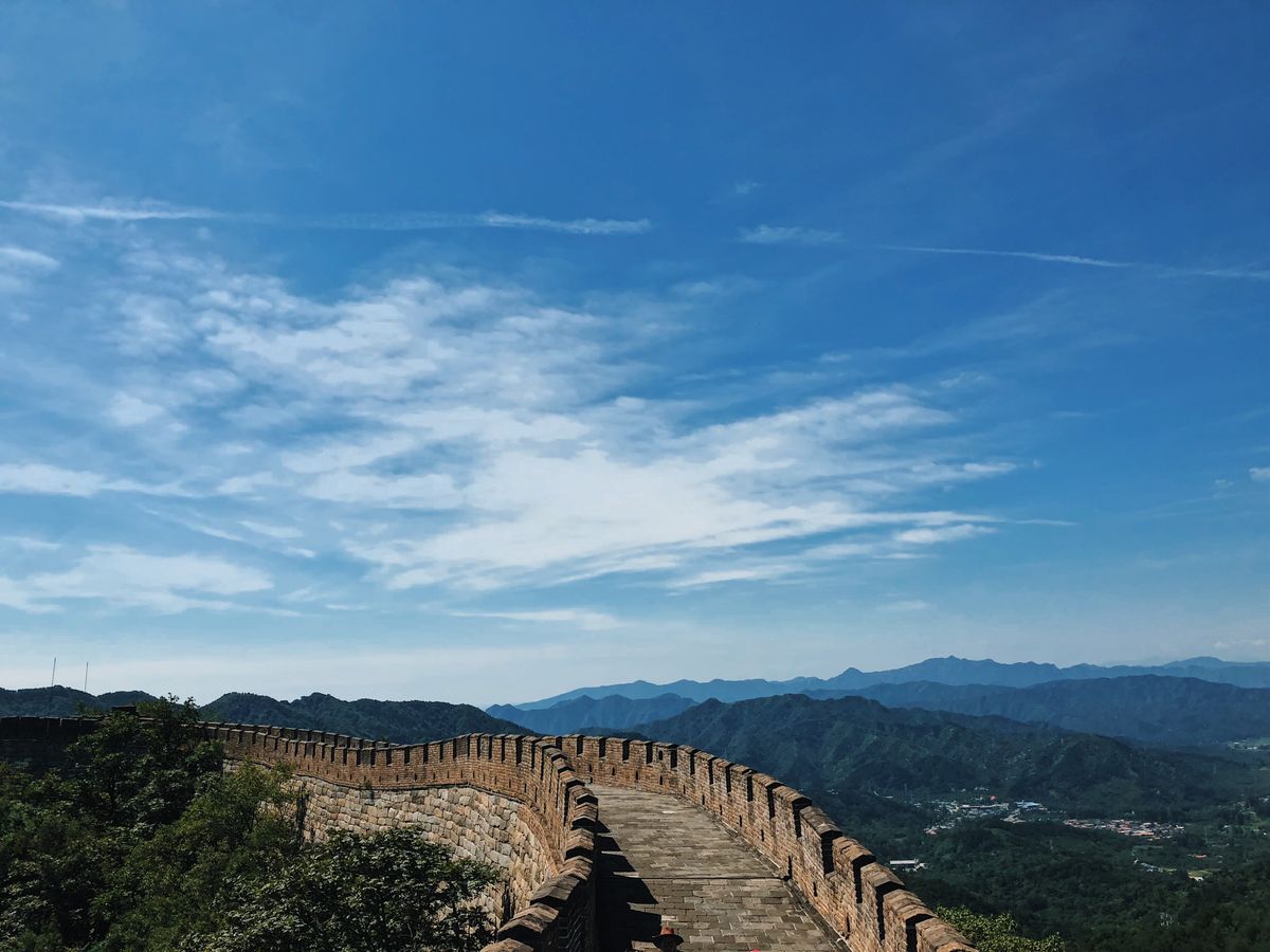 A breathtaking view of the Great Wall of China stretching across lush mountains under a vibrant blue sky.