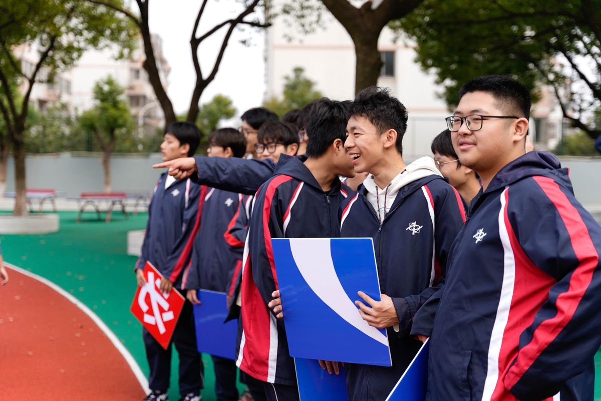 Asian students holding signs at an outdoor event in Wuxi, Jiangsu.