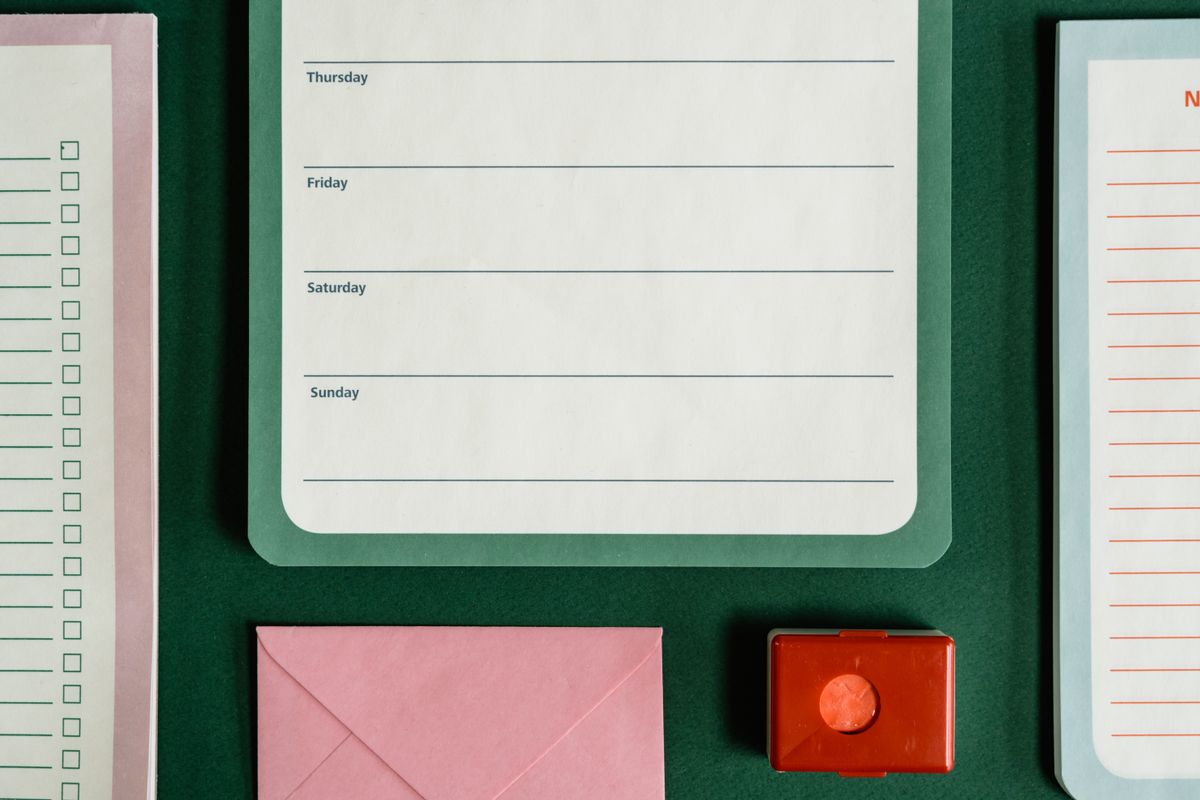 Flat lay of assorted stationery on a green surface, emphasizing organization.