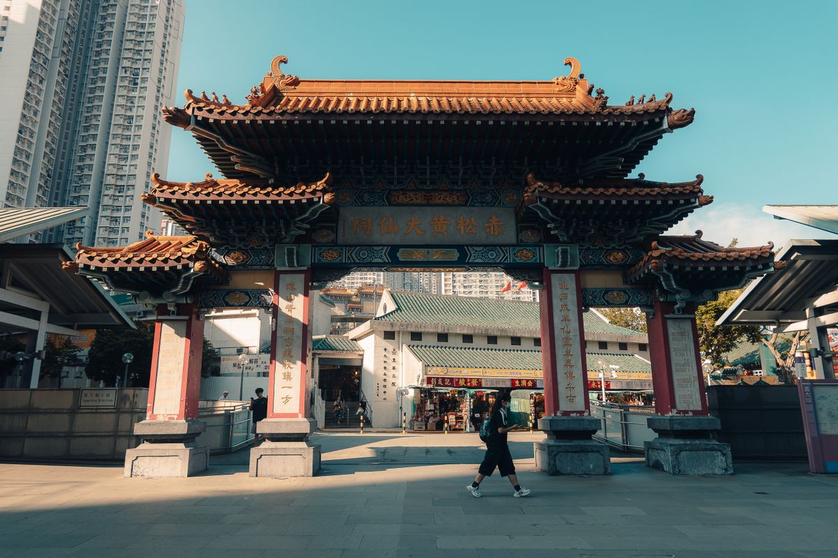 A traditional Chinese temple entrance in Hong Kong with a person walking by.