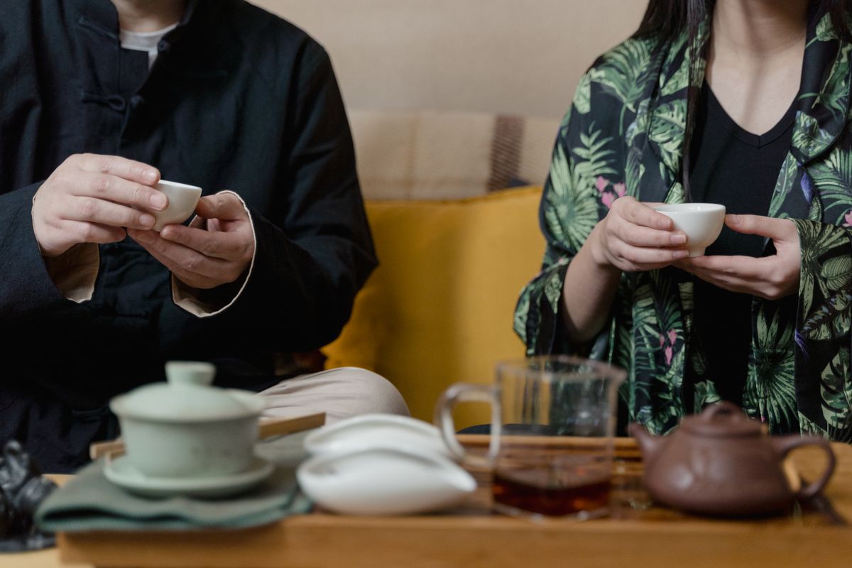 Close-up of two people holding teacups during a traditional tea ceremony.