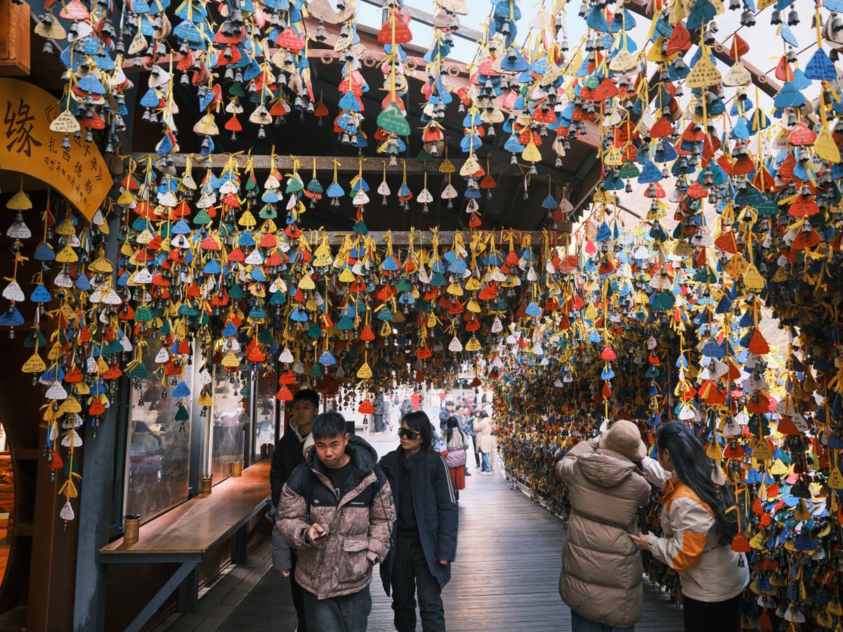 Crowded market scene with vibrant hanging wishing bells, capturing cultural ambiance.