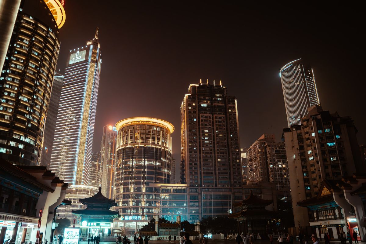 Vibrant city skyline at night with illuminated skyscrapers and modern architecture.